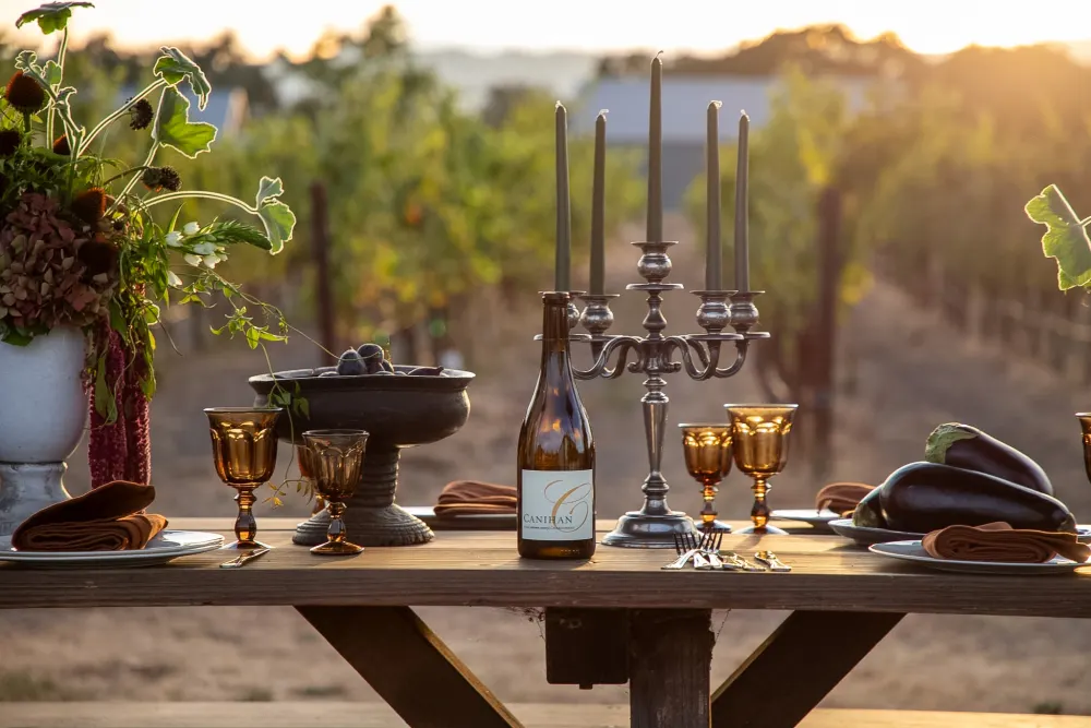 A wooden table at golden hour with silver candelabras, olive taper candles and amber goblets.