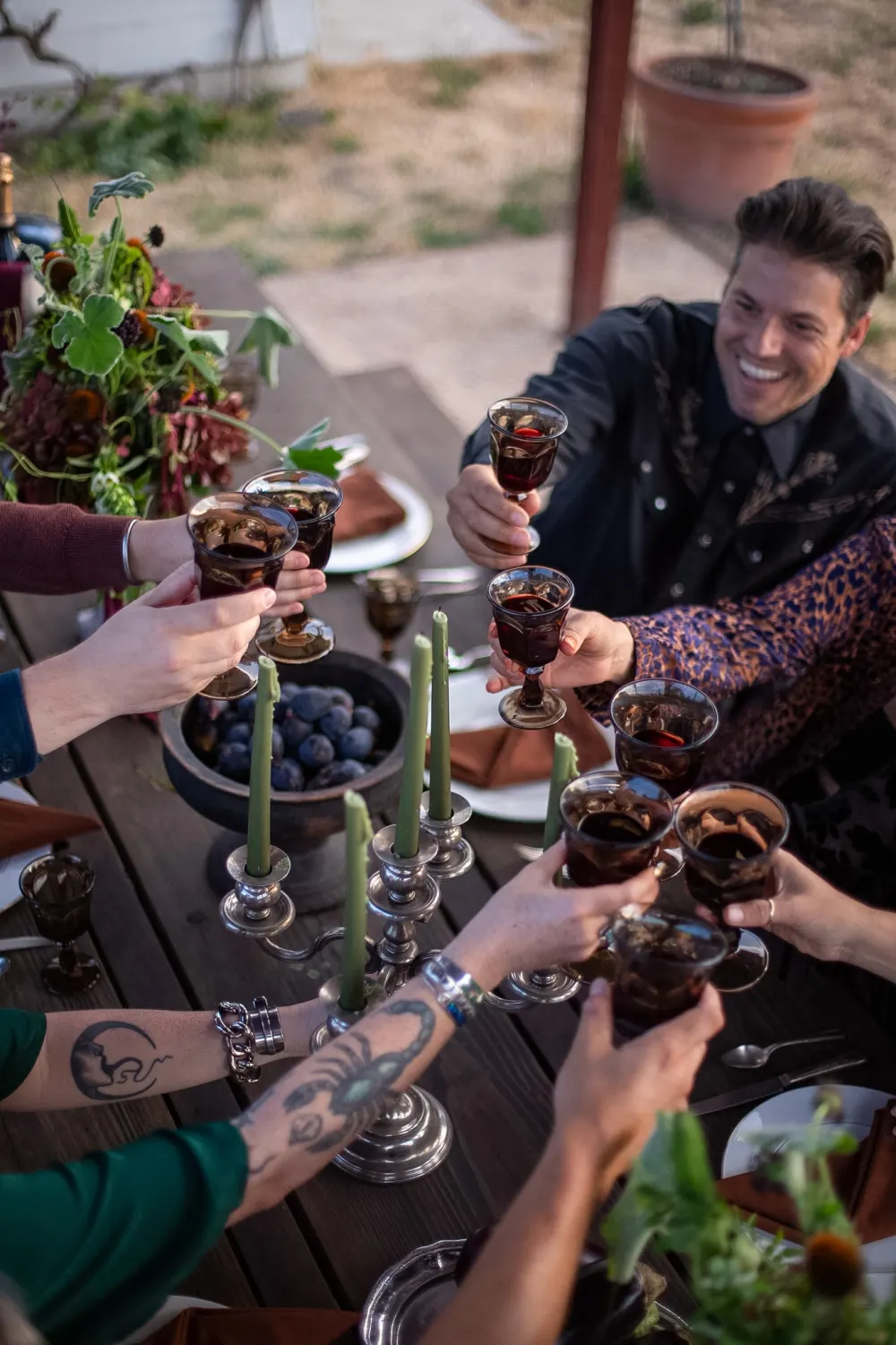 Guests toasting with amber goblets over a candlelit table.