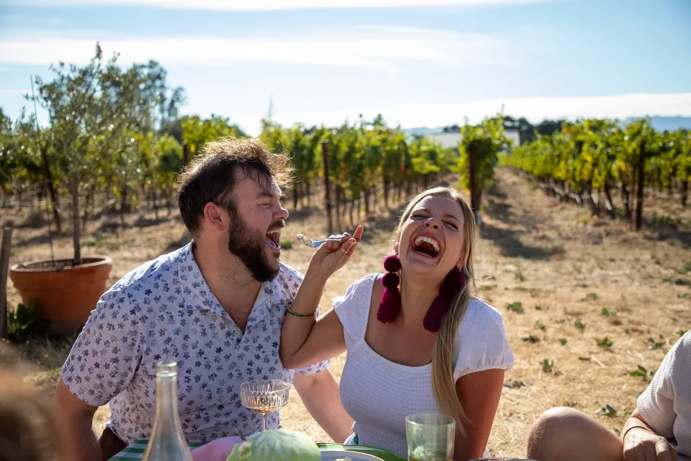 Friends laughing together outdoors in the vineyard.