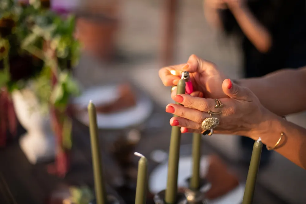 Hands lighting olive taper candles.