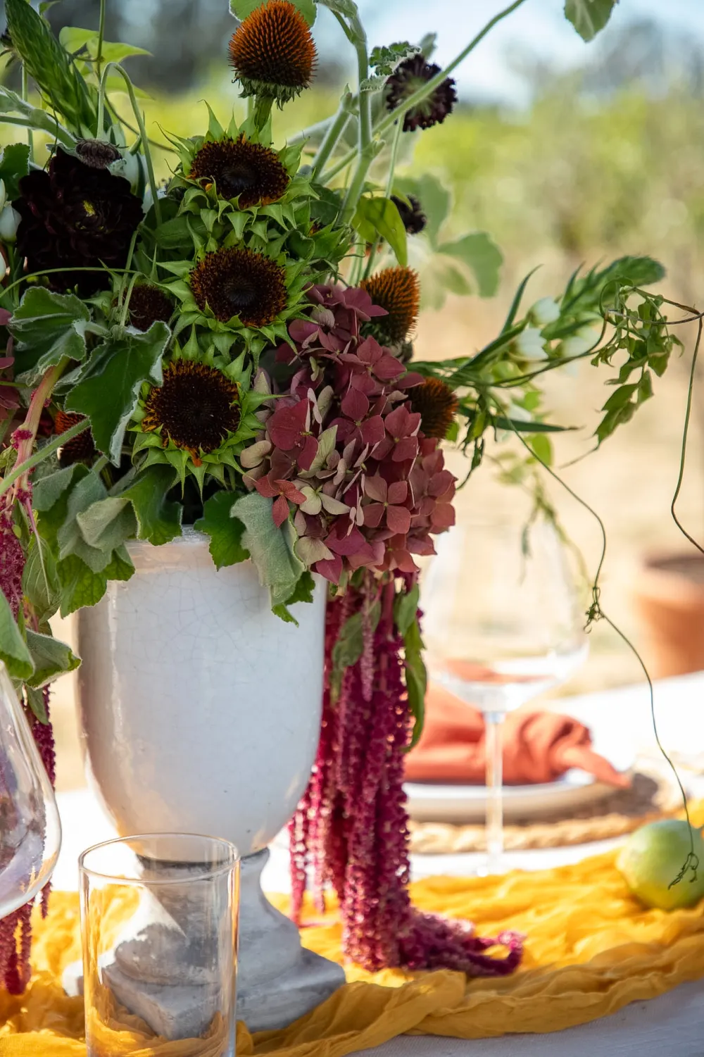 A white urn of dark dahlias and trailing amaranthus.