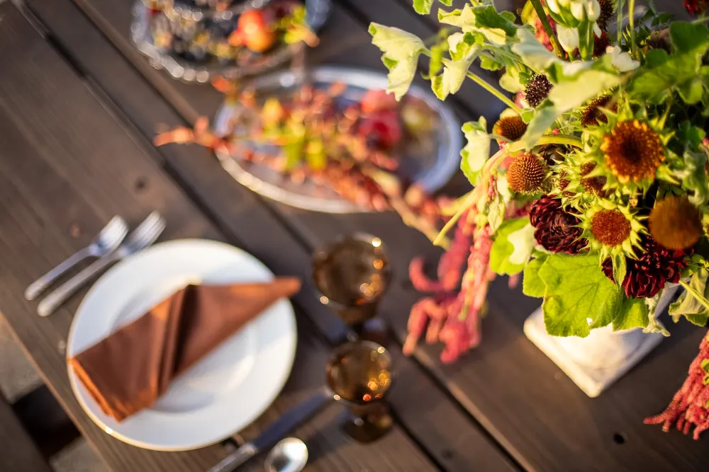 A white plate with a folded rust napkin and silver flatware.