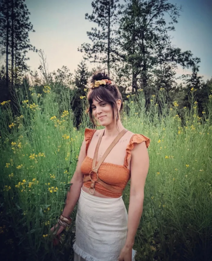 Melanie McDavid standing in a field of tall grass and wildflowers.
